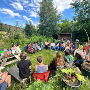 A group of people sitting outside in a circle, engaged in conversations